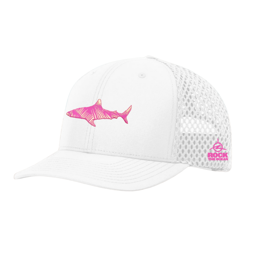 White cap with pink shark design on a sandy beach
